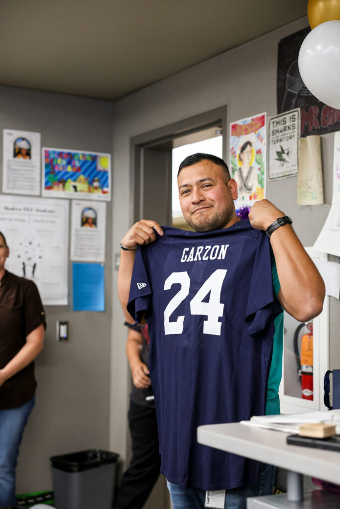 We Believe Champion holding up a personalized navy jersey with the name Garzon and the number 24
